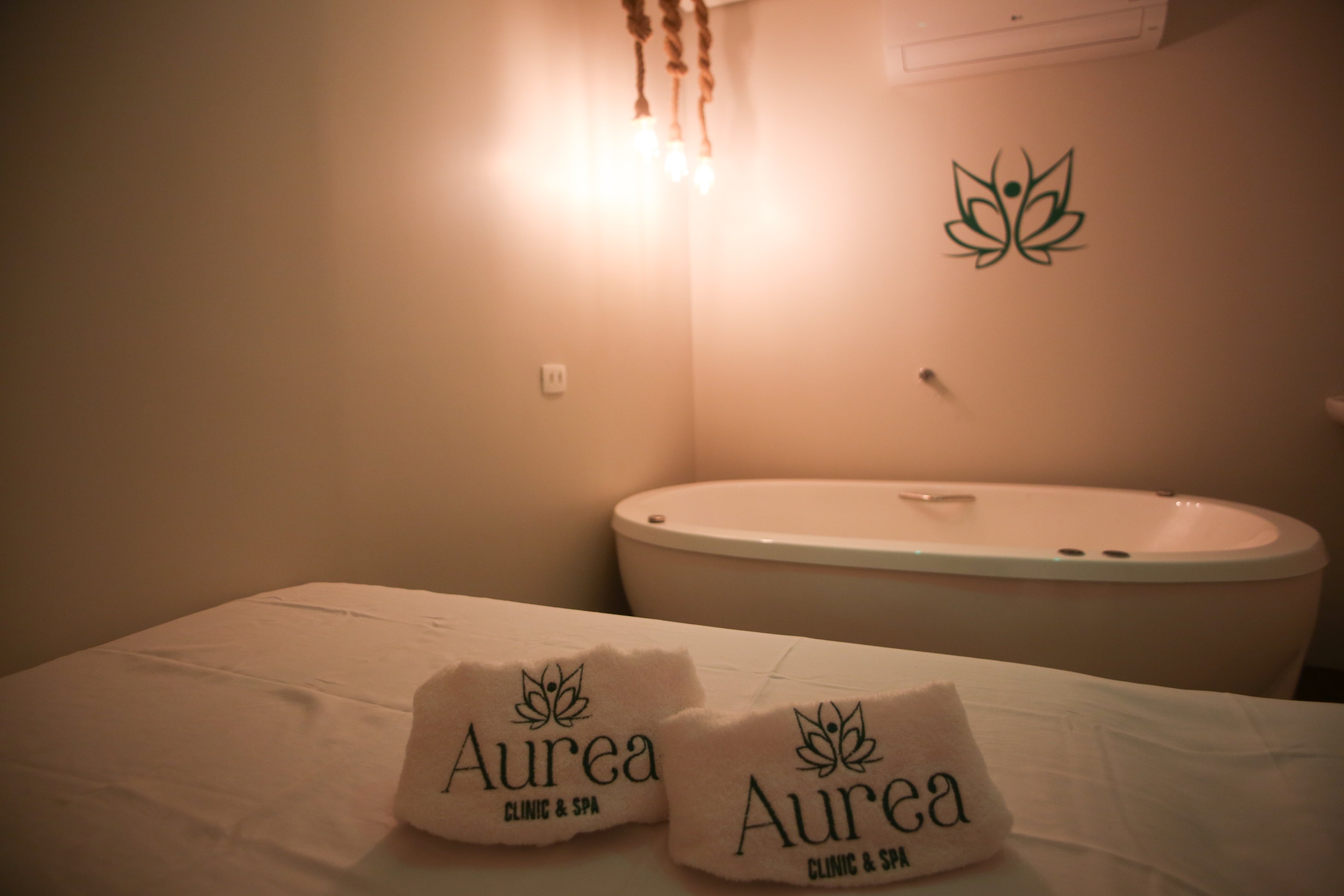 Sala de atendimento da Aurea Clinic & Spa, com a marca na parede e nas toalhas